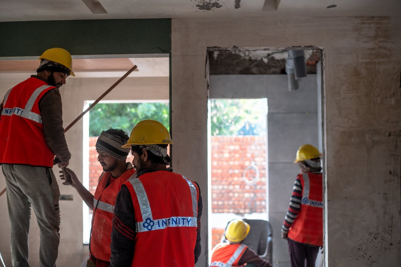 Construction workers wearing safety gear at an indoor building site in Delhi.